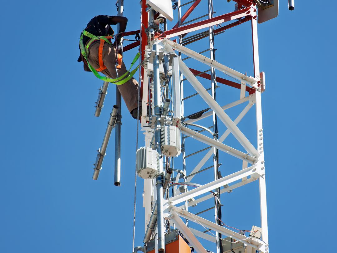 Tower Tech working up in thew tower, strapped to a harness to prevent danger. 